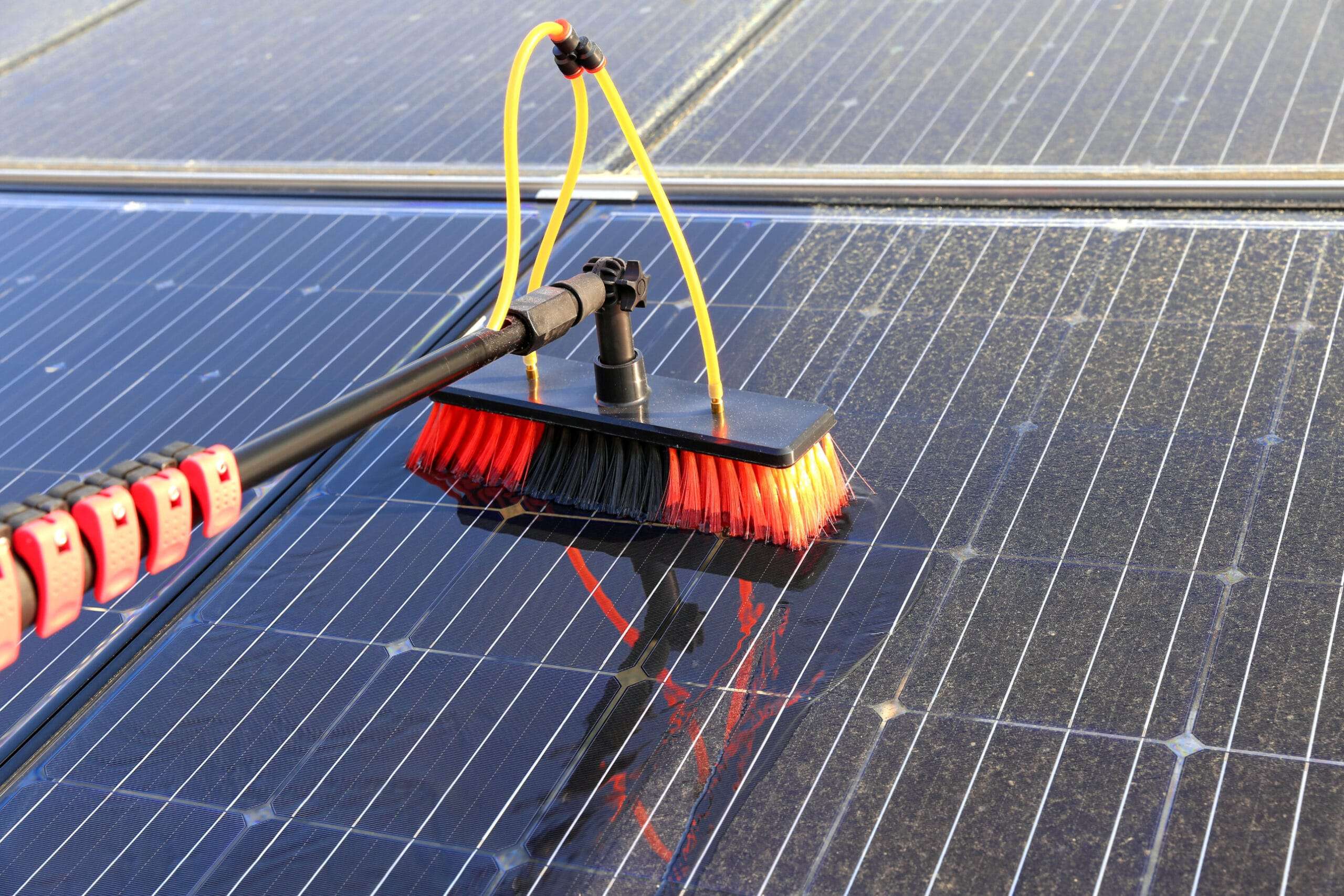 brush being used to clean solar panels
