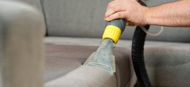 person wet vacuuming the sofa