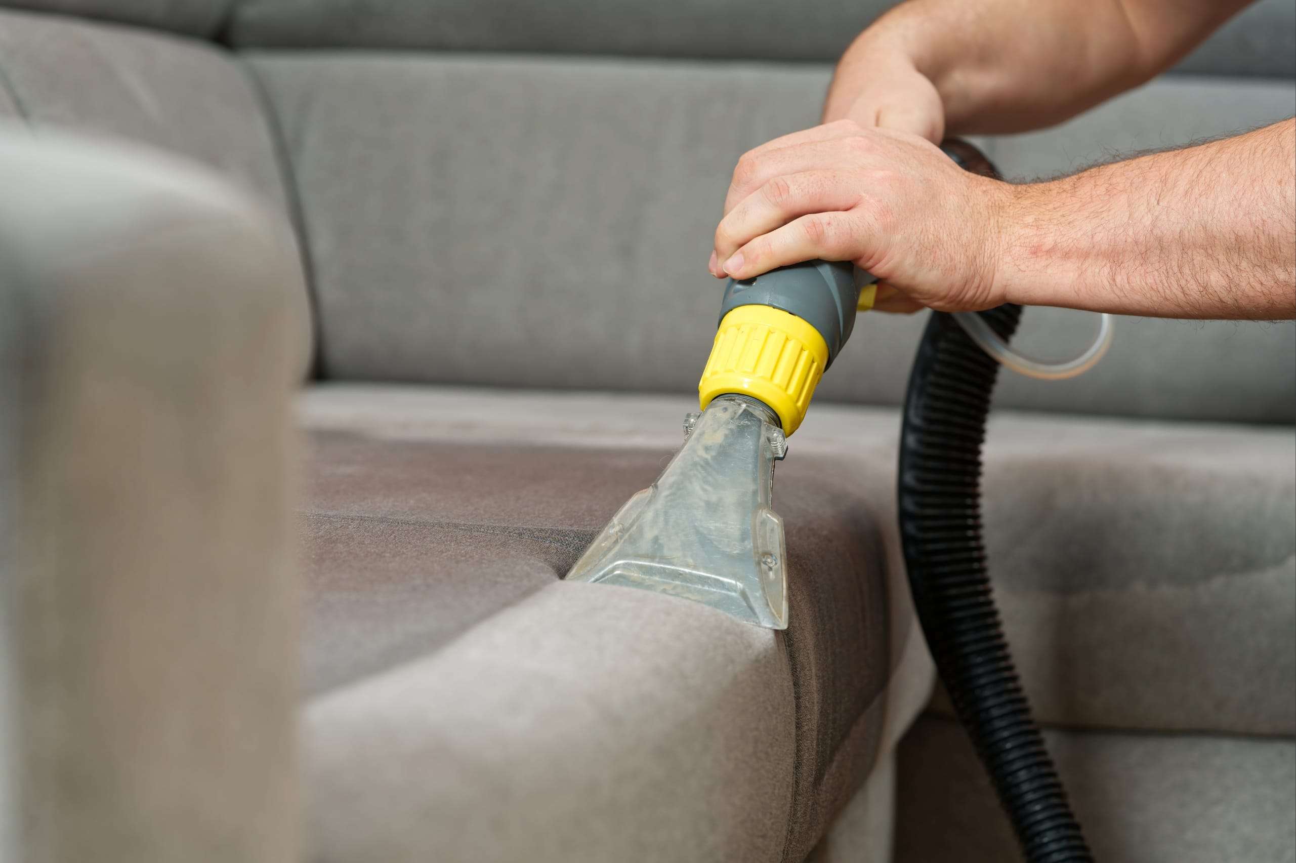 person wet vacuuming the sofa